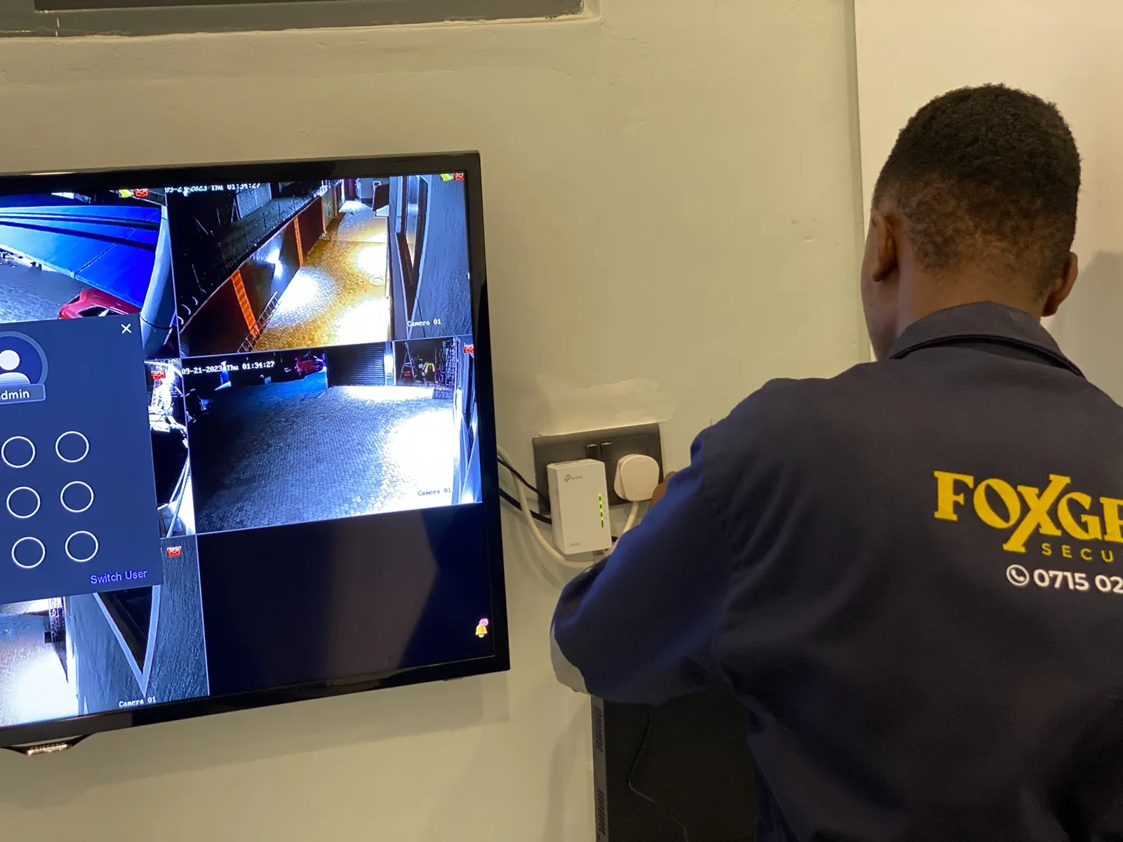 Foxgen technician setting up a wall-mounted screen showing several CCTV camera views